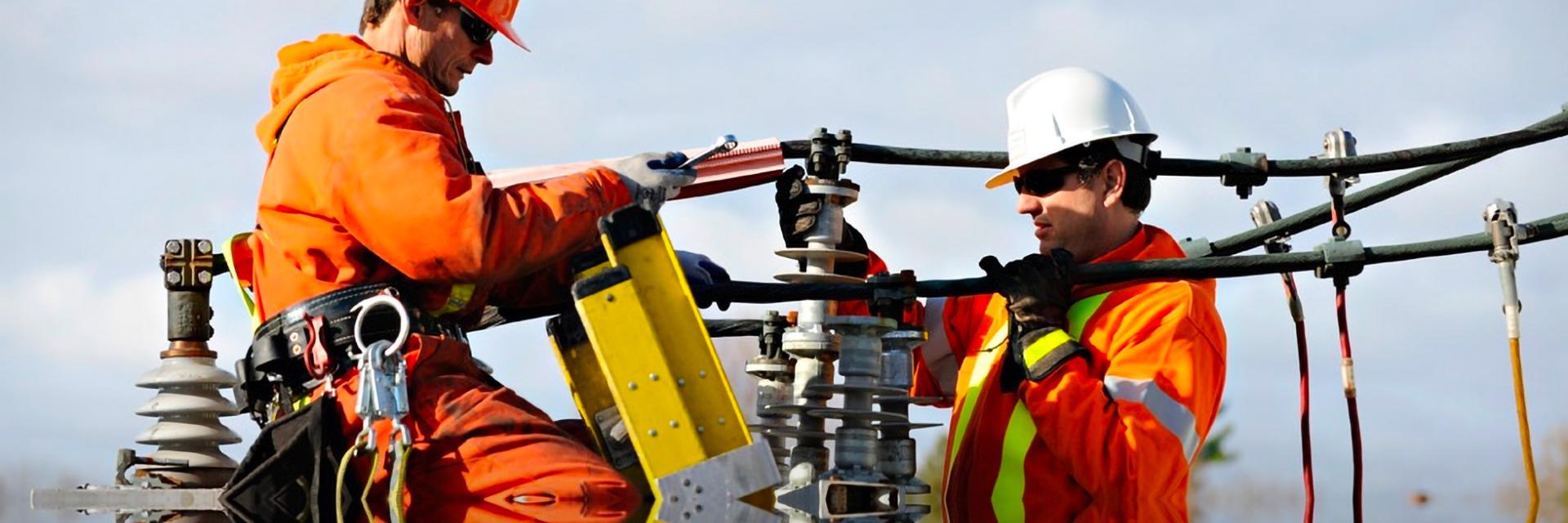 photo of two utility workers fixing a transformer